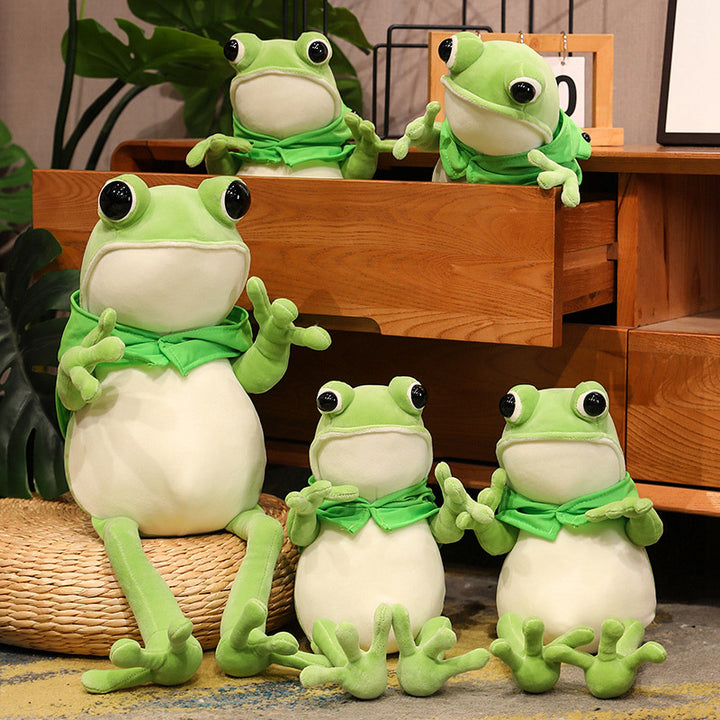 Une adorable peluche grenouille verte aux grands yeux noirs et à la cape verte, posant avec ses pattes avant tendues